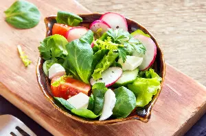 bowl of salad on top of a wooden board